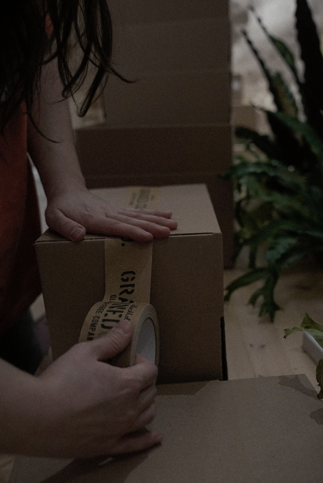 A woman putting on the tape on a Grained Gluten-Free Company Subscription box.